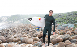 man in everyday sessions wetsuit with a surfboard