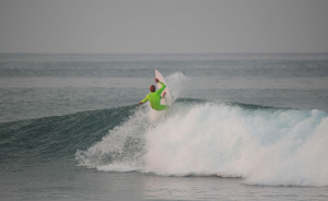 Man surfing a wave in Lime green Xcel Comp wetsuit
