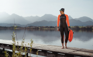 Woman in open water swimming kit by a lake