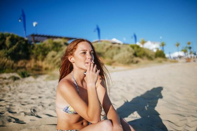 Smoking girl on the beach